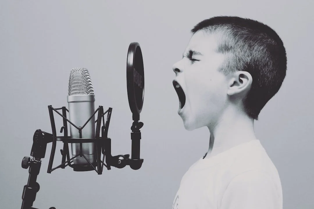 A young boy shouting into a microphone