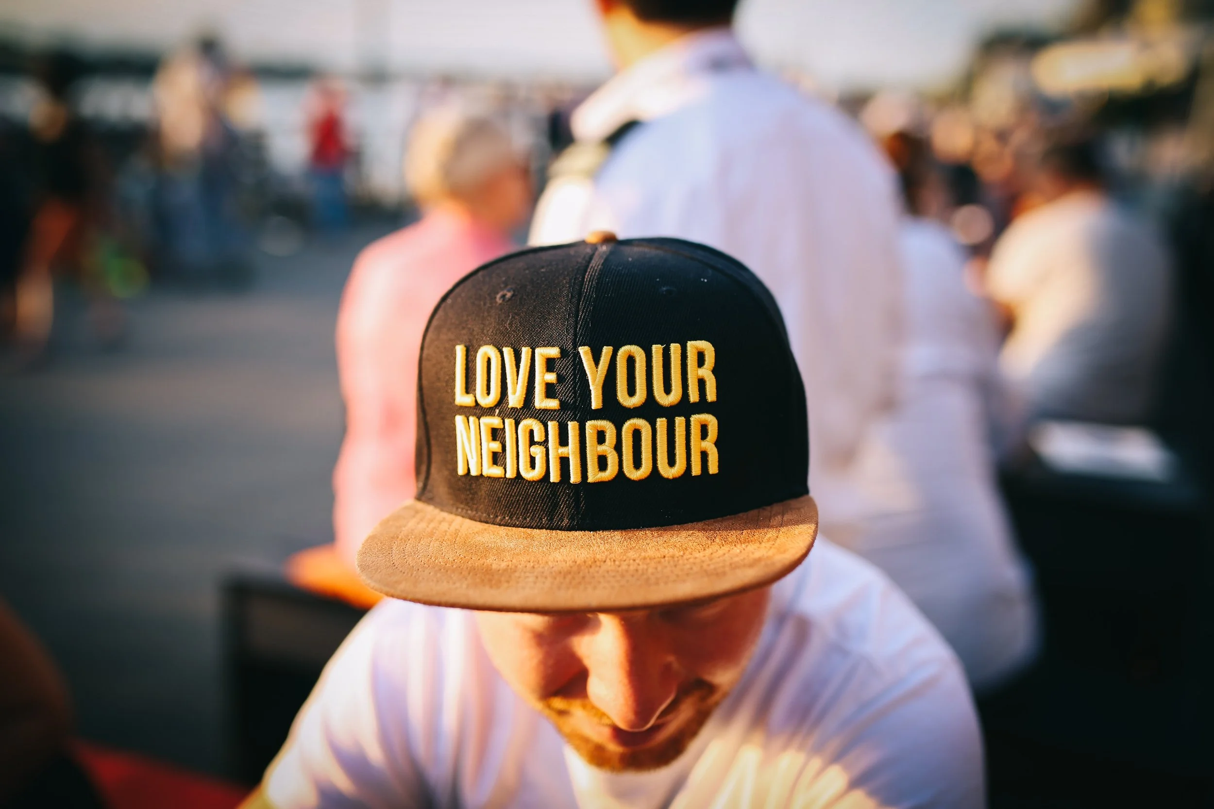 Person wearing a Love Your Neighbour cap