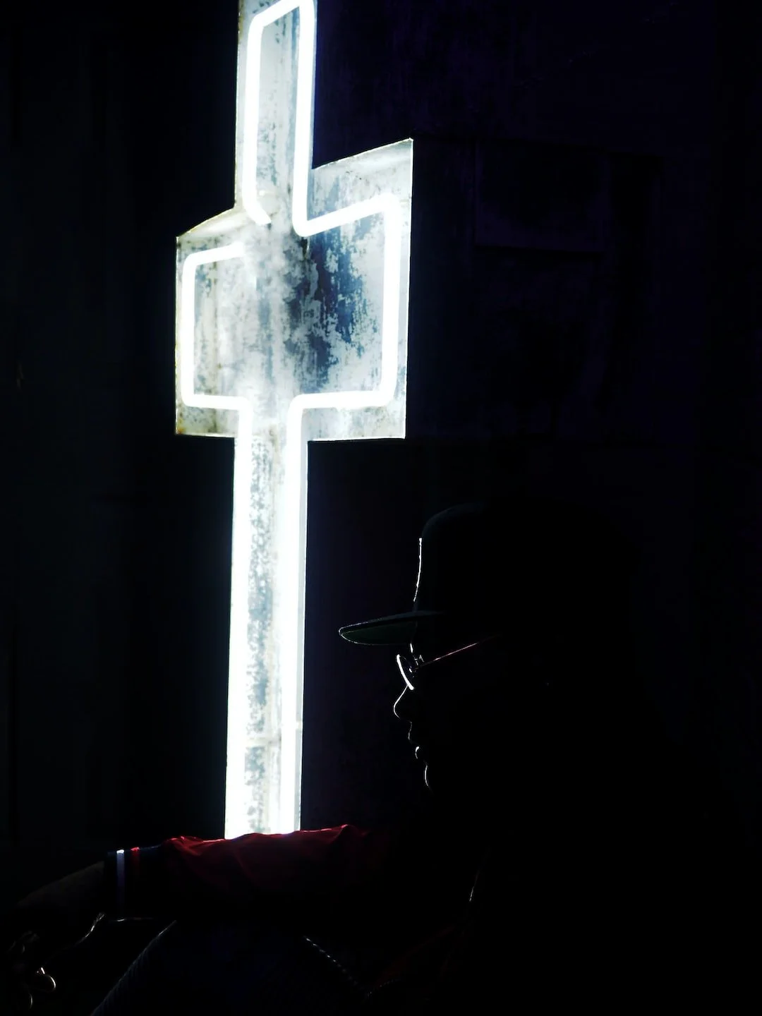 A person sitting in front of a neon cross